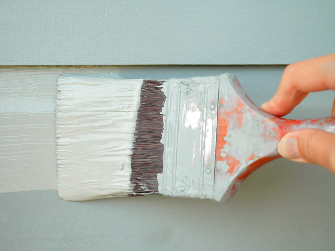 Hand holding brush painting wall